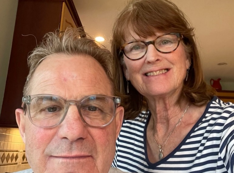 Scott and his wife at home smiling at the camera.