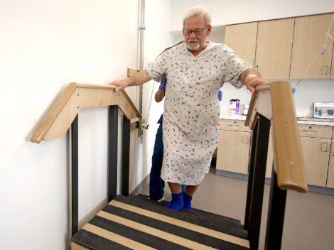 A patient climbs stair equipment in the therapy gym to work to gain mobility and strength.