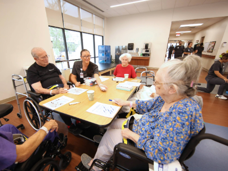 Patients sit around the table with an occupational therapist and play bingo.