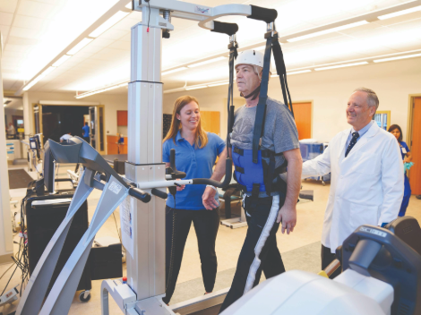 A patient learns to walk again using a ceiling ambulatory treadmill. 