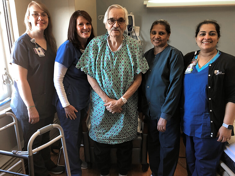 Free from his ventilator, John stands unassisted in his hospital room with his team of caregivers.