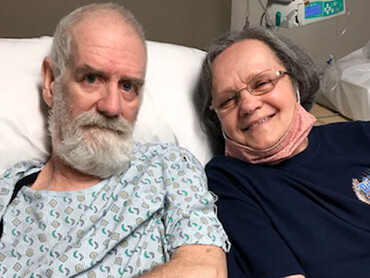 Kenneth sits with his wife Joyce on his hospital bed.