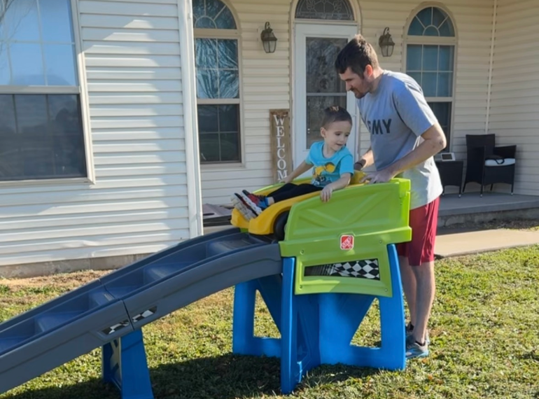 Brian and his son playing outside on a slide.