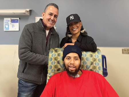 Justin and his parents smiling at the camera.