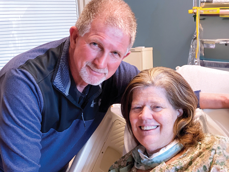 Mary and her husband smiling at the camera.