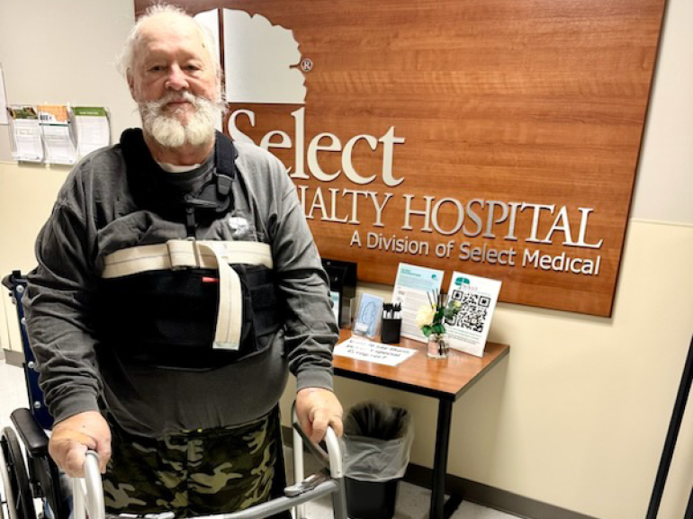 Allen Cochran stands using a rolling walker.