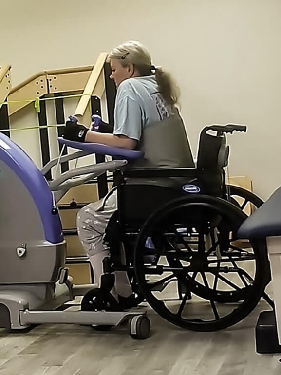 Angela Fawley, sitting in a wheel chair, doing training exercises.