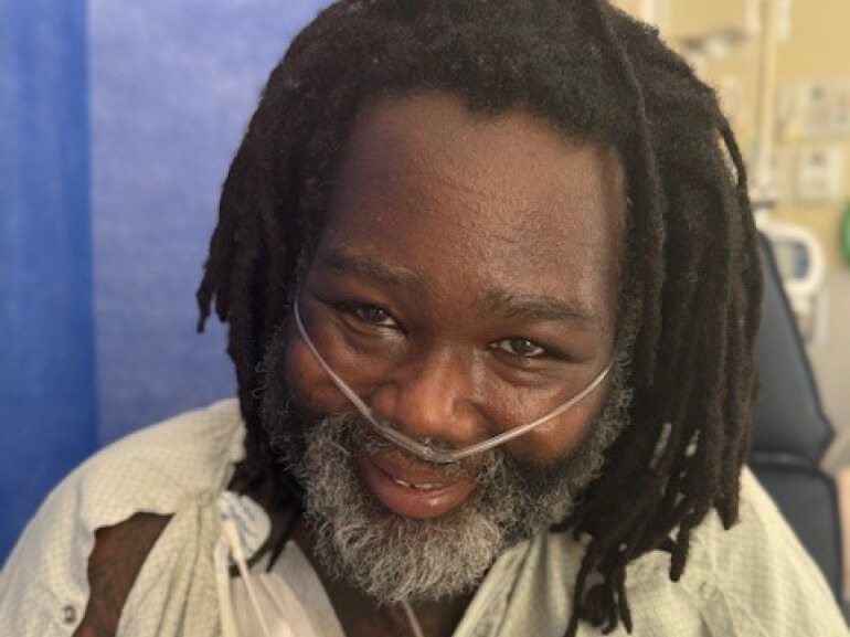 Darrell Robinson sits in his hospital room, smiling for the camera.