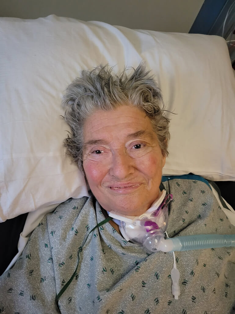 Paulette Crawford laying in a hospital with a ventilator attached to her throat.