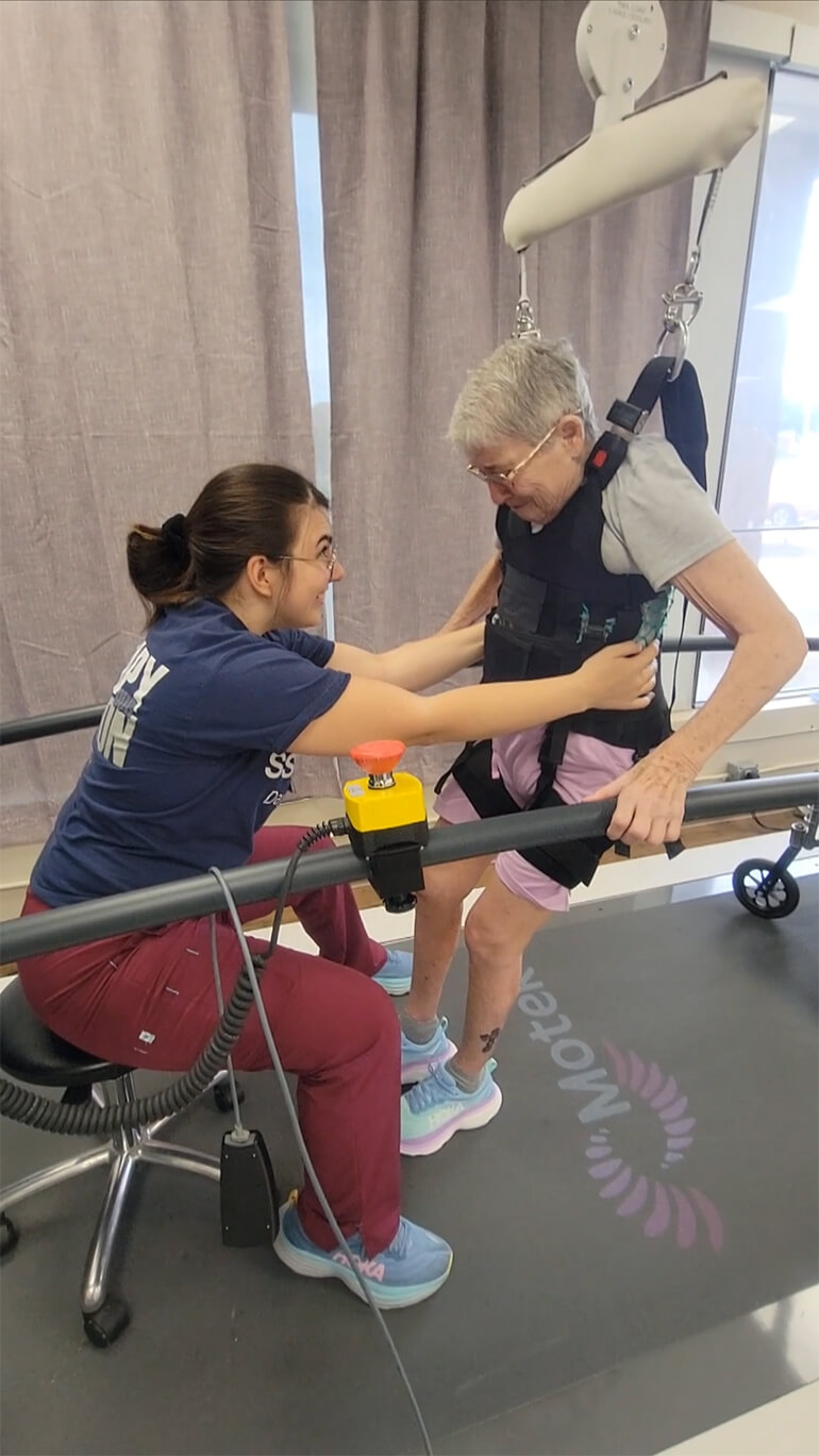 Paulette Crawford doing leg training exercises with a therapist.