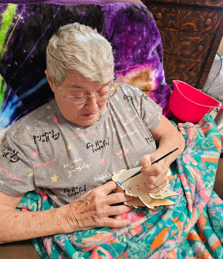 Paulette Crawford sitting in her chair doing crafts.