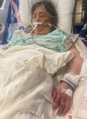 Stacy lays in her hospital bed battling complications from heart surgery.