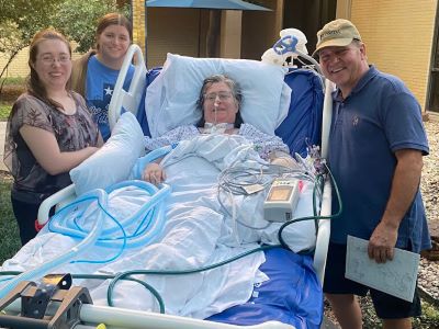 Stacy lays in her hospital bed with her family by her side.