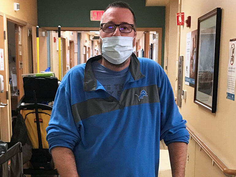 Steven Peterson standing and wearing a mask in a hospital hallway.